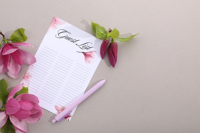 Guest list, pen and beautiful flowers on grey background, flat lay. Space for text