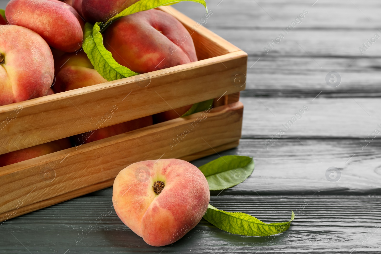 Photo of Fresh ripe donut peaches on grey wooden table, closeup
