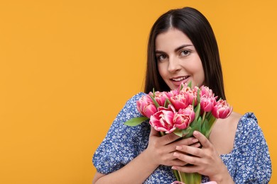 Photo of Happy young woman with beautiful bouquet on orange background. Space for text