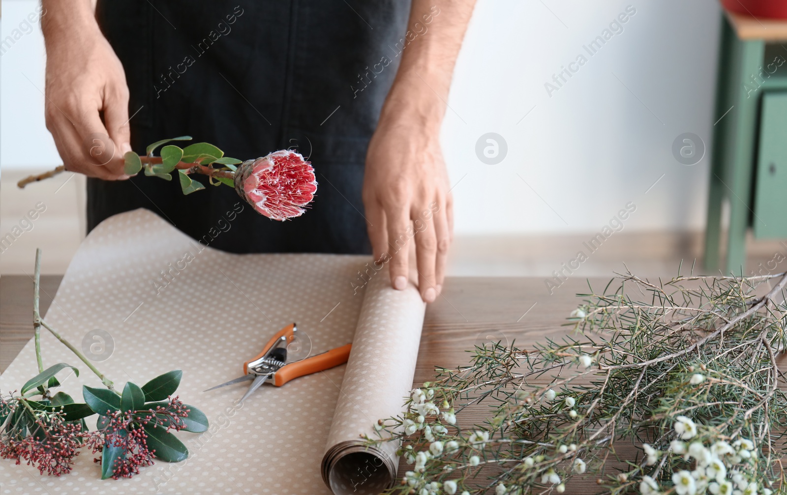 Photo of Male florist creating beautiful bouquet at table, closeup