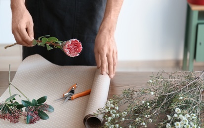 Photo of Male florist creating beautiful bouquet at table, closeup