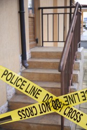 Image of Yellow crime scene tape blocking way to stairs outdoors