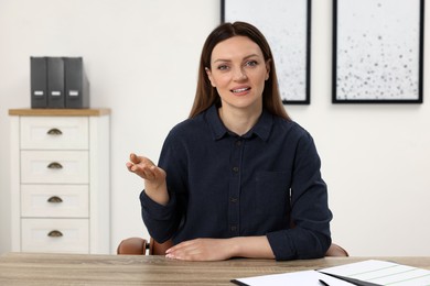 Woman having video chat at wooden table in office, view from web camera