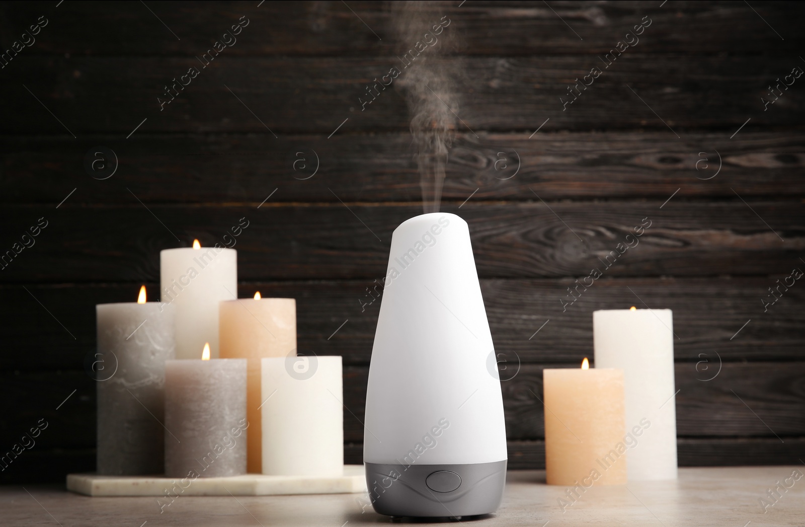 Photo of Modern aroma humidifier with candles on table against dark wooden background, space for text