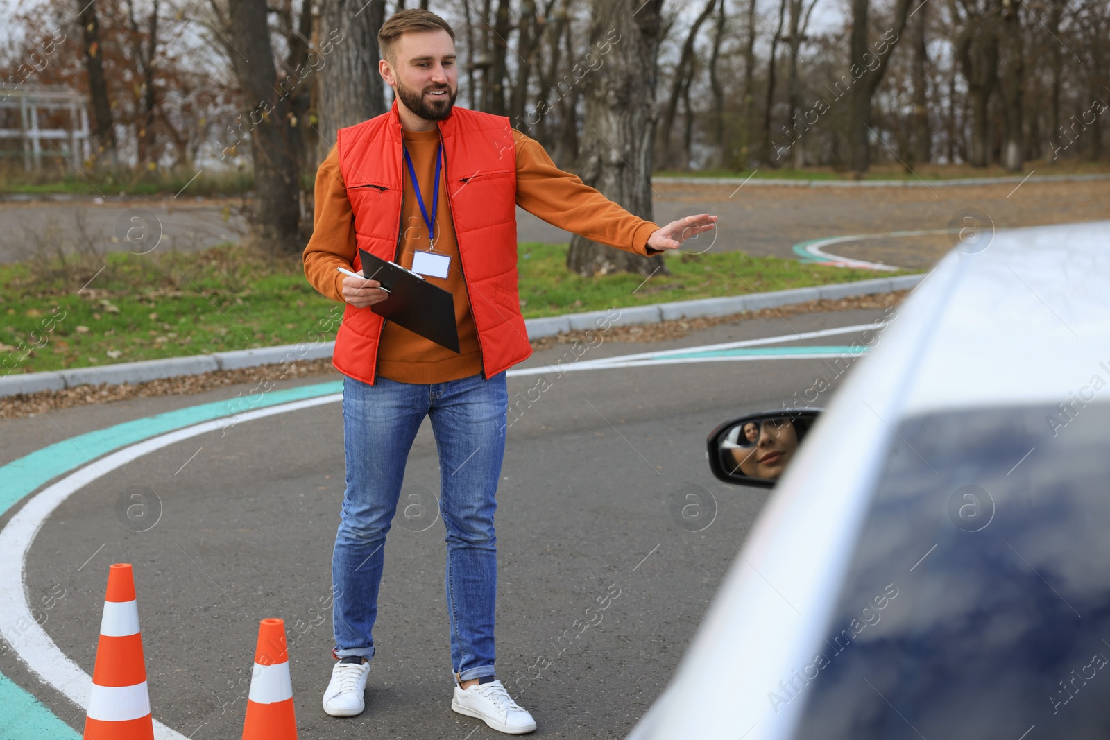 Photo of Instructor near car with his student during exam at driving school test track