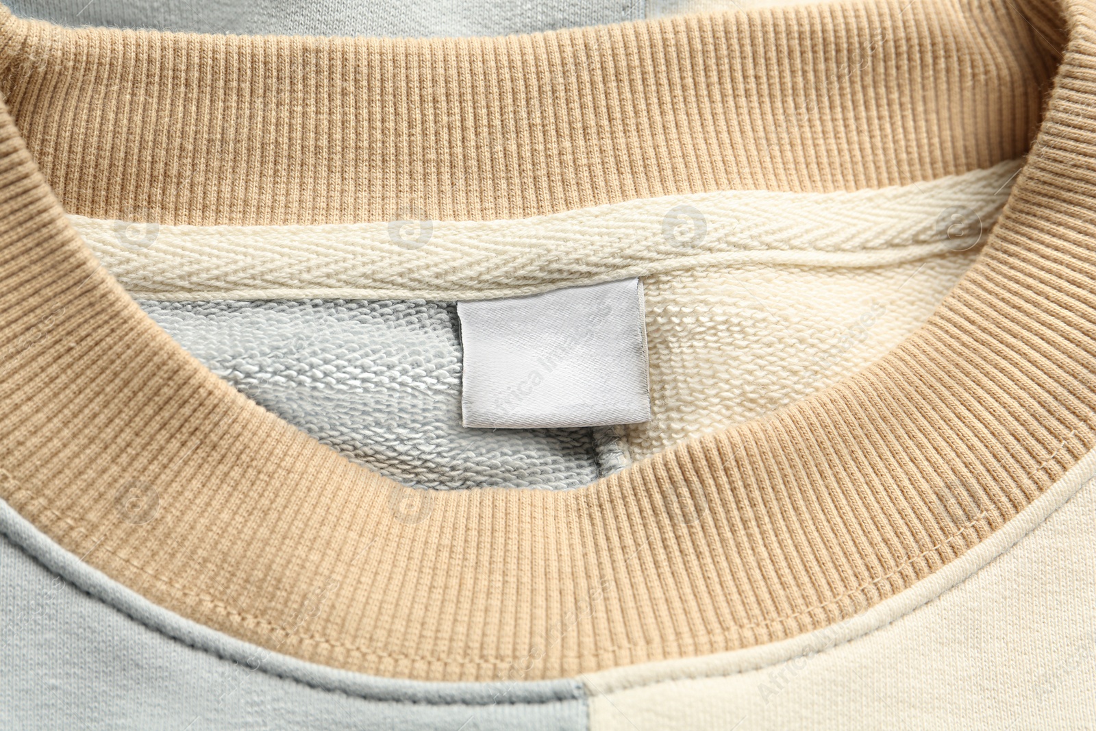 Photo of Blank clothing label on stylish sweater, top view