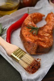 Photo of Fresh marinade, fish, brush and other products on table, closeup