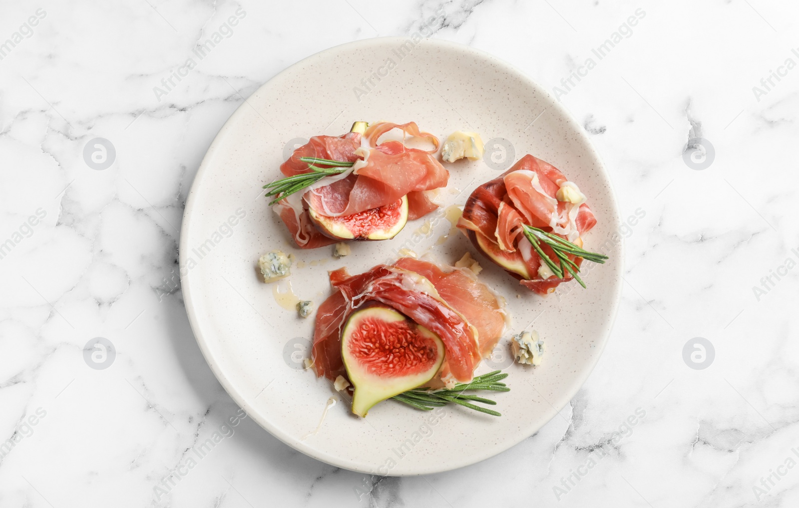 Photo of Delicious ripe figs and prosciutto served on white marble table, top view