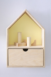 Photo of House shaped shelf with toys on white wall. Interior design