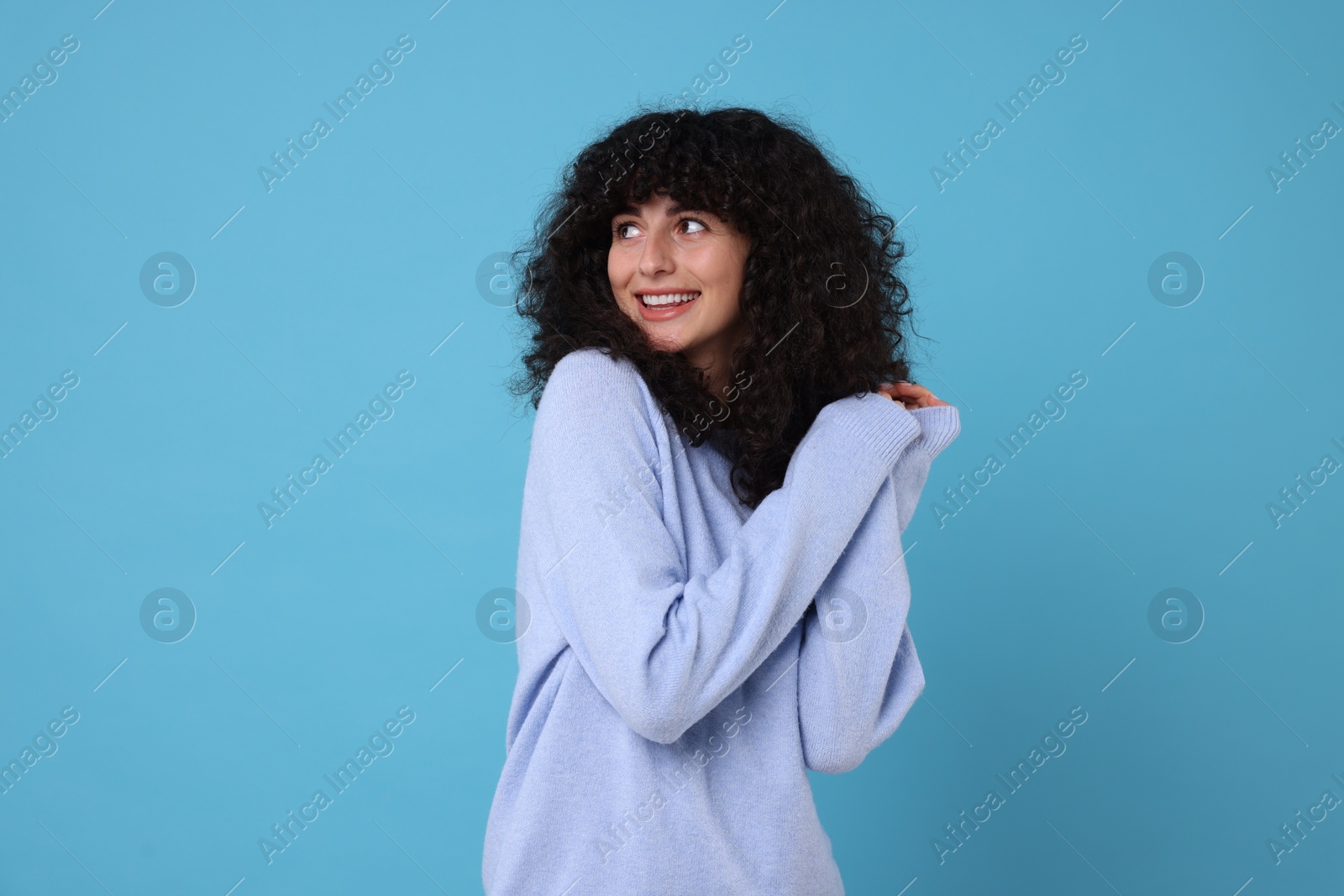 Photo of Happy young woman in stylish warm sweater on light blue background