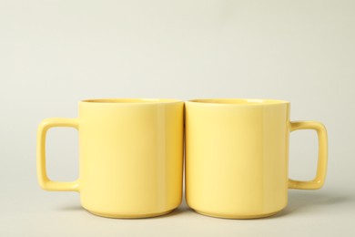 Photo of Two yellow ceramic mugs on light grey background