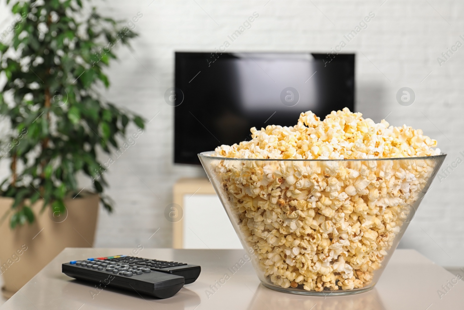 Photo of Popcorn and TV remote controls on table in living room