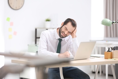 Young man suffering from headache in office