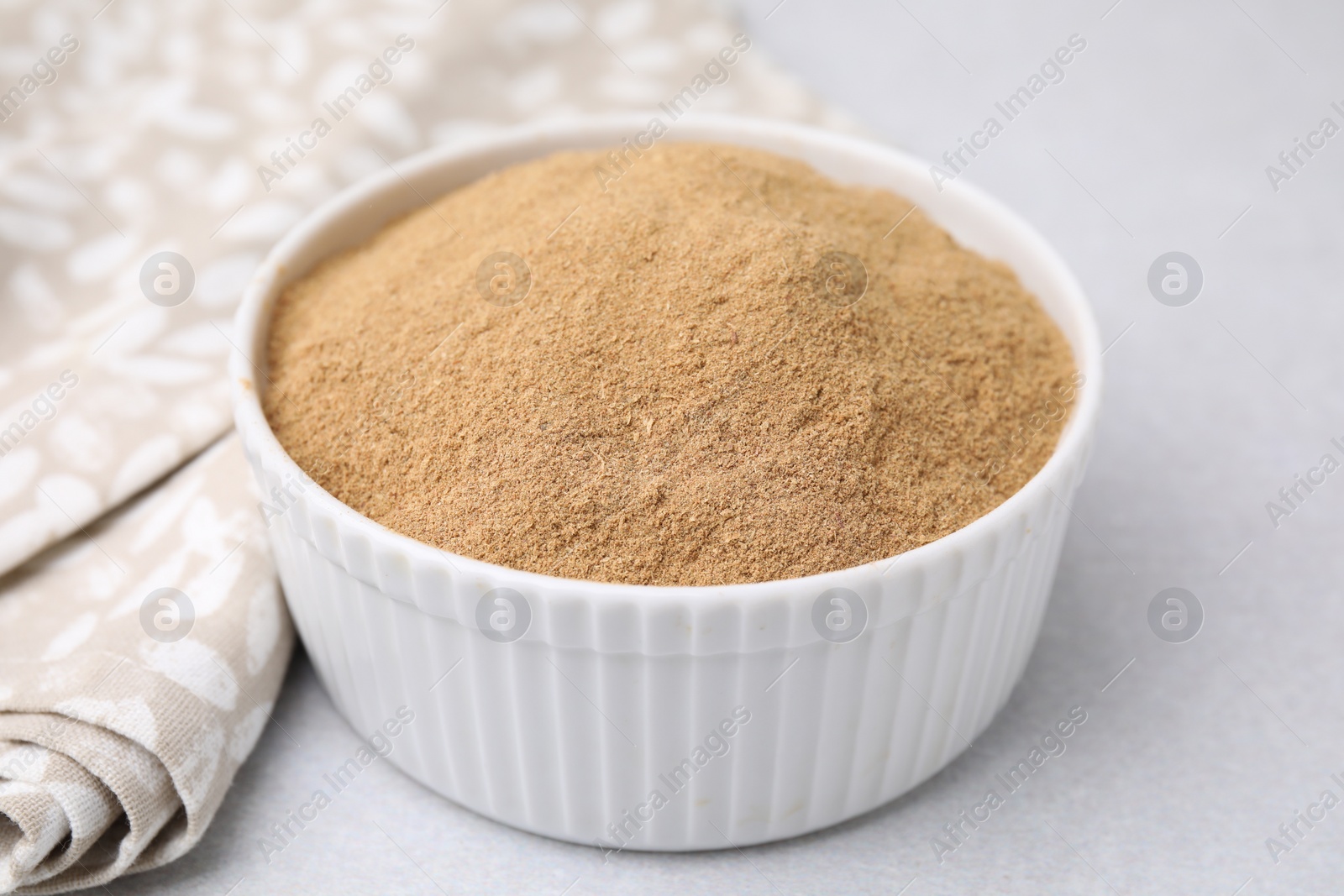 Photo of Dietary fiber. Psyllium husk powder in bowl on light grey table, closeup