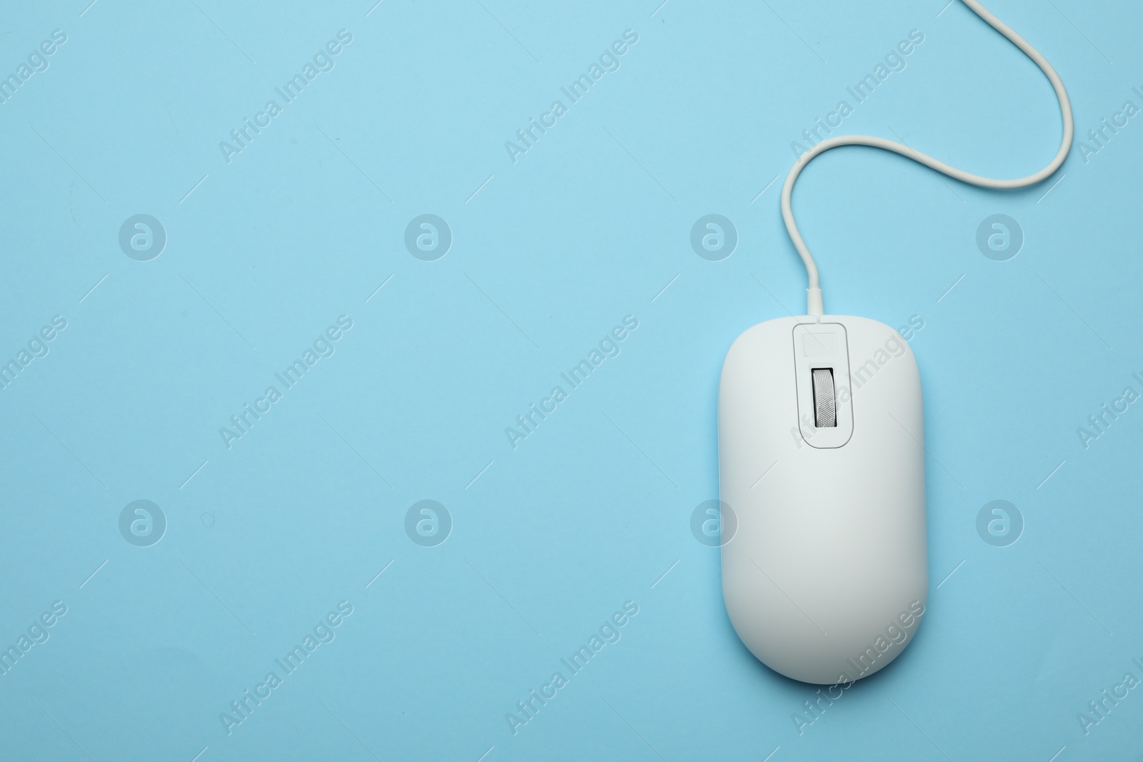 Photo of Wired computer mouse on light blue background, top view. Space for text