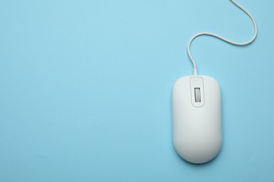Photo of Wired computer mouse on light blue background, top view. Space for text