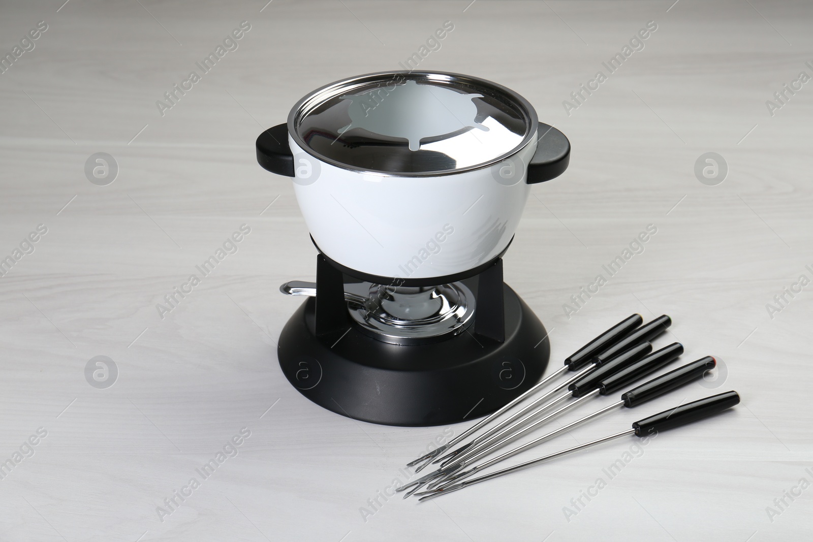 Photo of Fondue set on white wooden table. Kitchen equipment