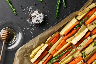 Photo of Tray with parsnips, carrots and other products on black table, flat lay