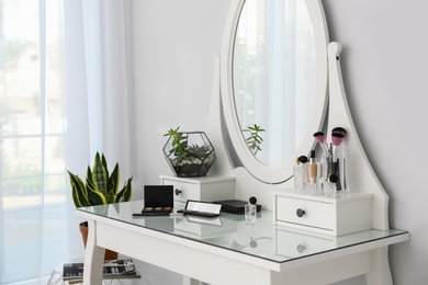 Photo of Cosmetics on dressing table with mirror at home. Stylish room interior