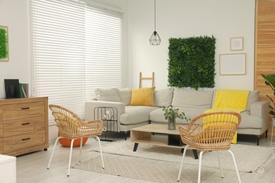 Green artificial plant wall panel and comfortable furniture in cozy living room. Interior design