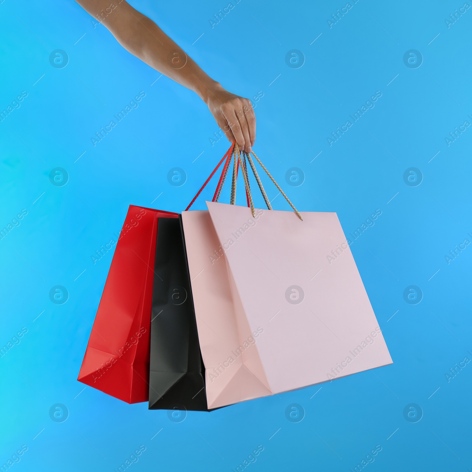 Photo of Woman with paper shopping bags on light blue background, closeup