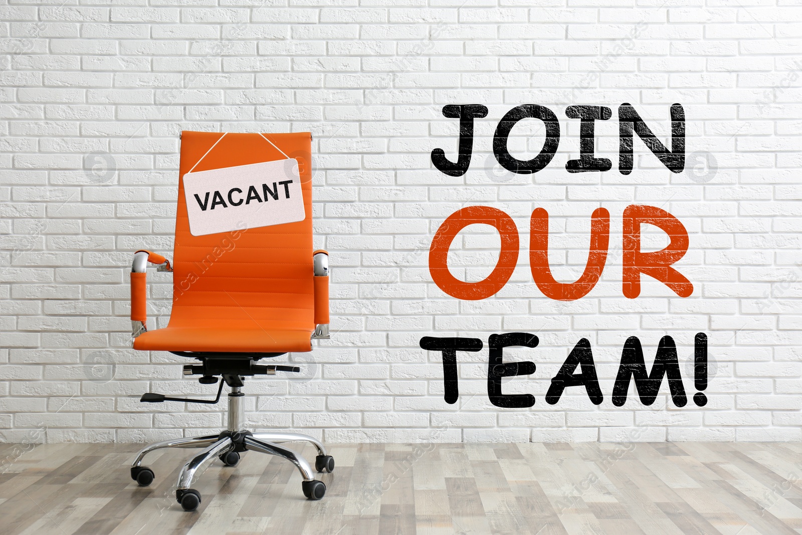 Image of Join our team! Orange office chair with sign VACANT near white brick wall indoors