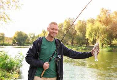 Man with rod fishing at riverside on sunny day. Recreational activity