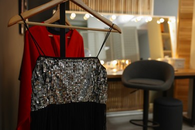 Photo of Makeup room. Chair near dressing table with stylish mirror indoors, focus on clothes rack