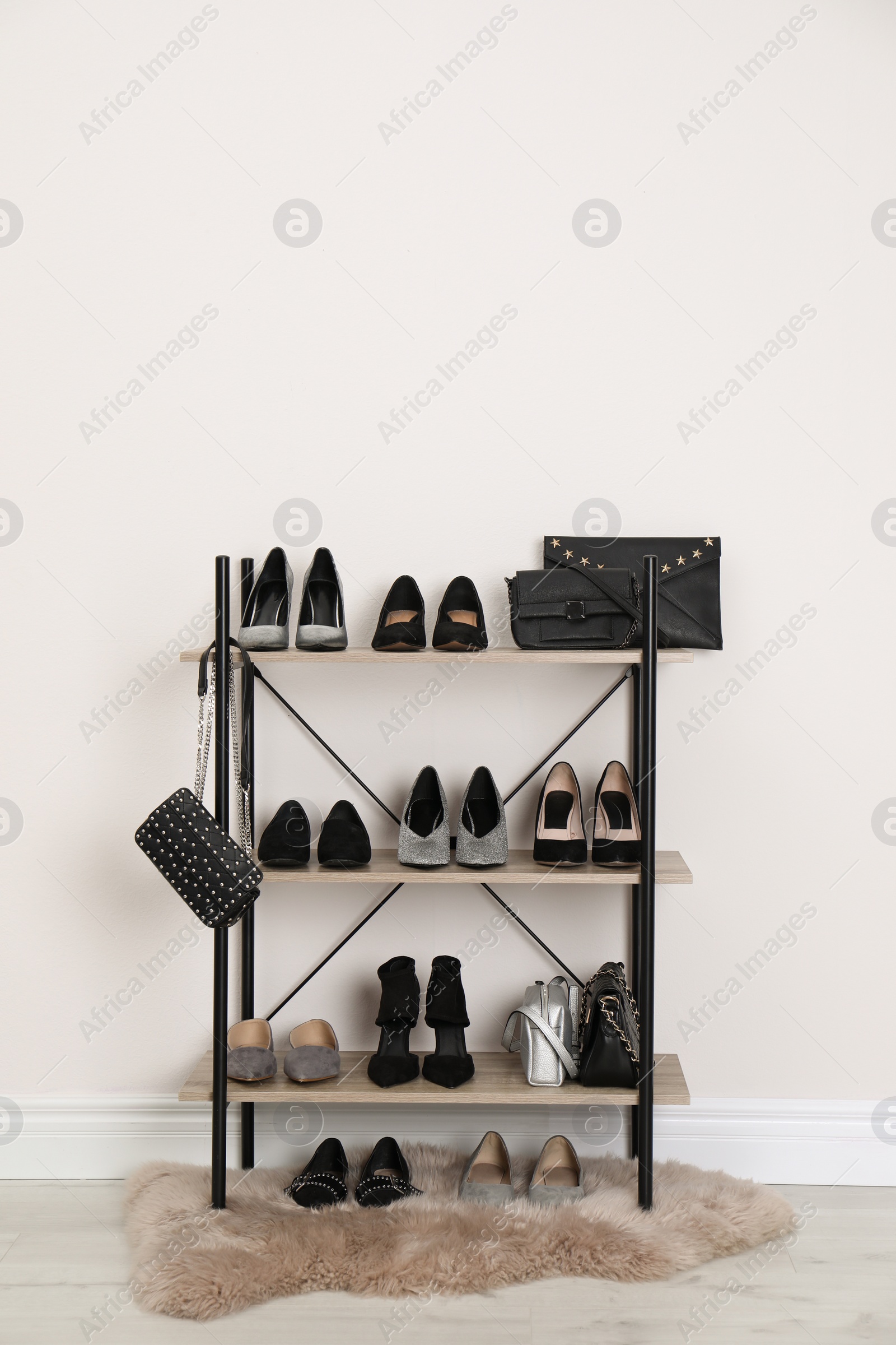 Photo of Shelving unit with stylish shoes and purses near white wall. Element of dressing room interior