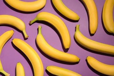 Photo of Ripe yellow bananas on purple background, flat lay