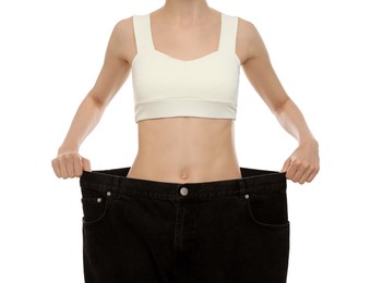 Young woman wearing big jeans after weight loss on white background, closeup