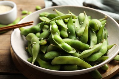 Photo of Green edamame beans in pods served on wooden table, closeup