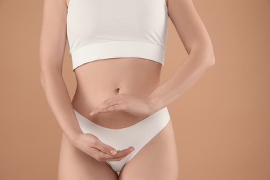 Gynecology. Woman in underwear on beige background, closeup