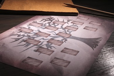Photo of Blank family tree, notebook and pencil on wooden table, closeup