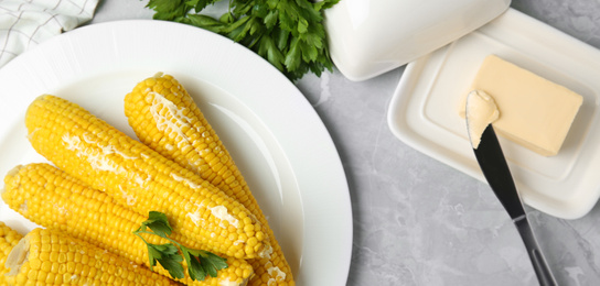 Tasty boiled corn cobs served on light grey marble table. Banner design