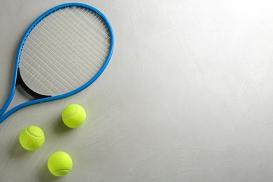 Photo of Tennis racket and balls on grey table, flat lay. Space for text