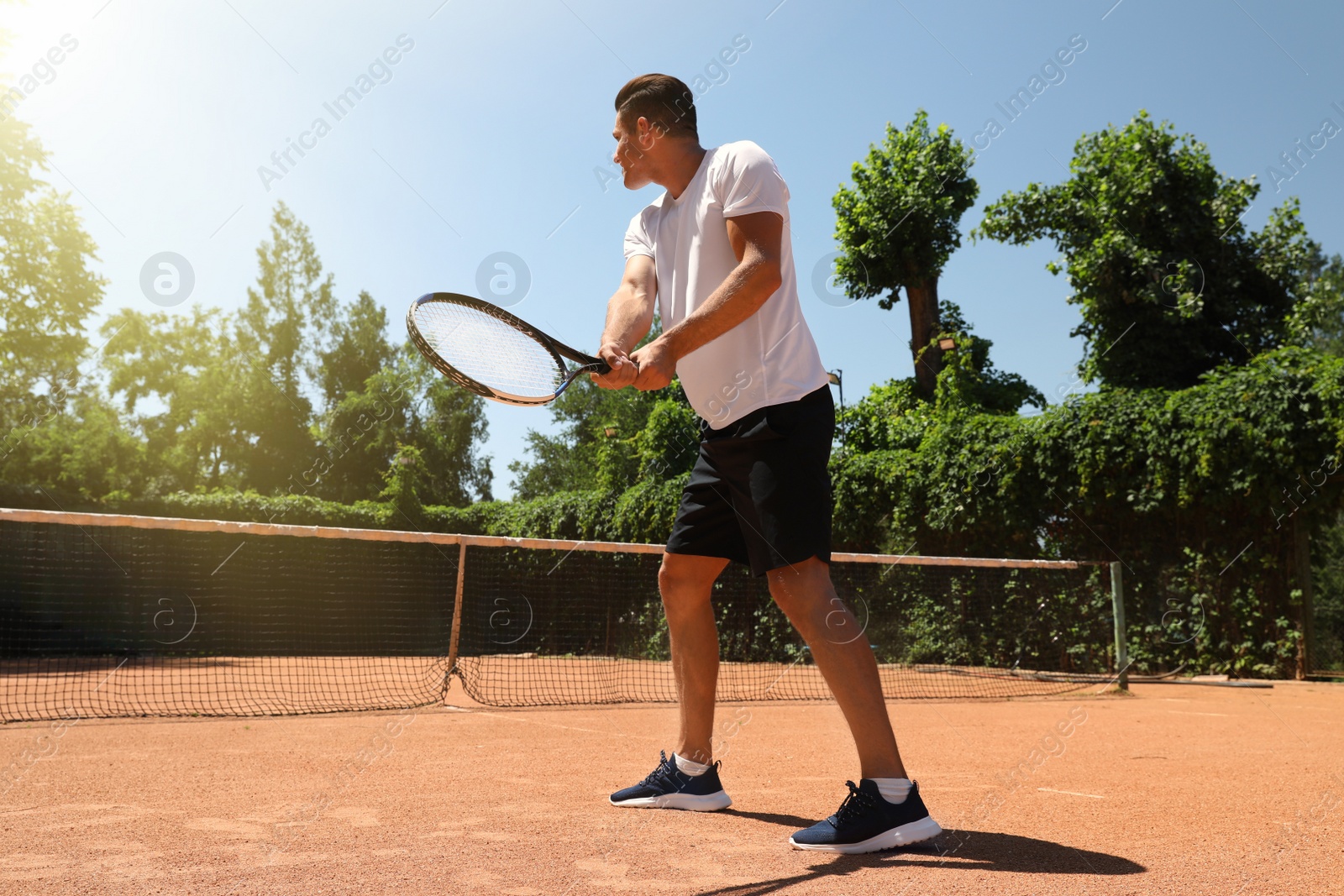 Photo of Man playing tennis on court during sunny day