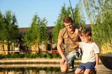 Photo of Dad and son fishing together on sunny day
