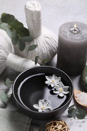 Photo of Beautiful composition with herbal massage bags, spa products and flowers on light grey table