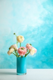 Photo of Vase with beautiful ranunculus flowers on color background