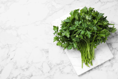 Photo of Bunch of fresh green parsley on white marble table, top view. Space for text