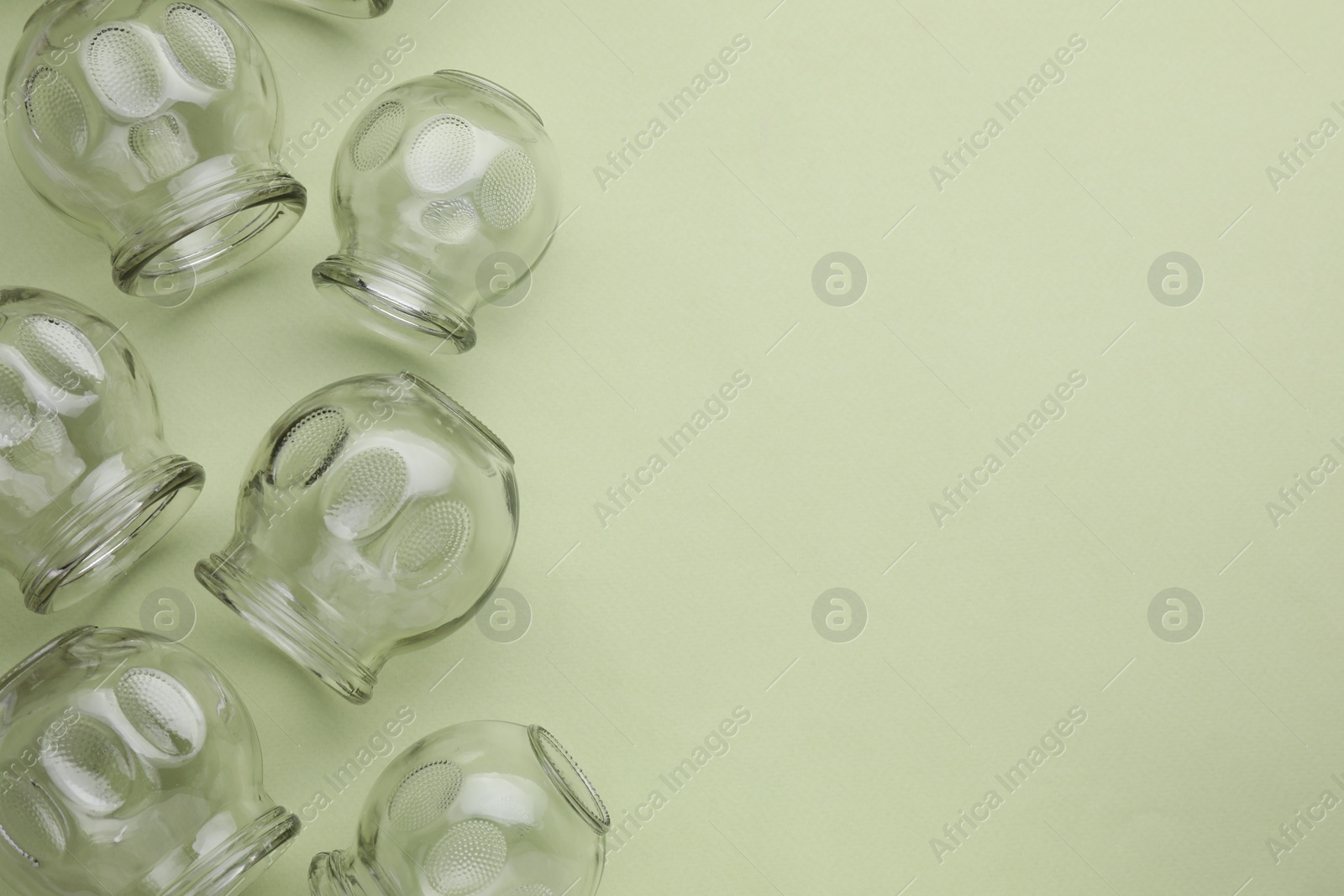 Photo of Glass cups on light olive background, flat lay and space for text. Cupping therapy
