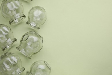 Photo of Glass cups on light olive background, flat lay and space for text. Cupping therapy