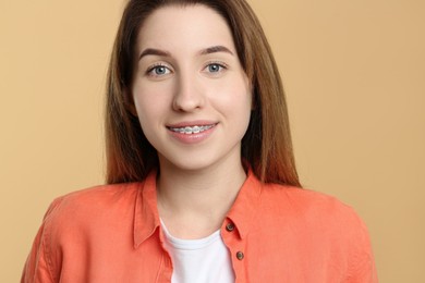 Photo of Portrait of smiling woman with dental braces on beige background