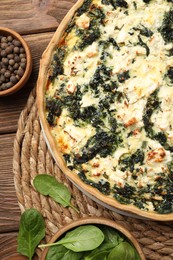 Delicious homemade quiche and spinach leaves on table, flat lay