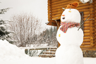 Photo of Funny snowman with hat and scarf outdoors. Winter vacation