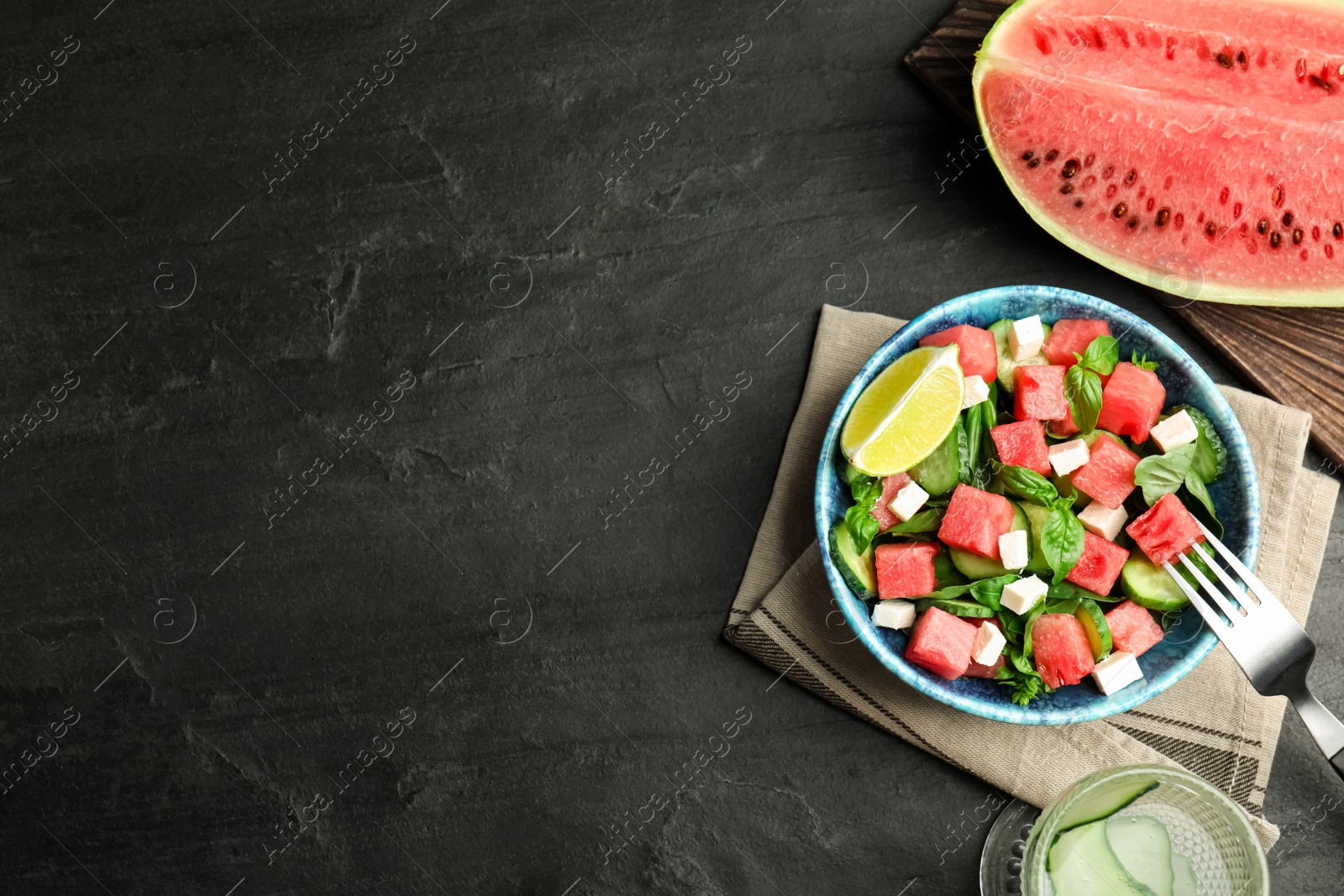 Photo of Delicious salad with watermelon served on black table, flat lay. Space for text