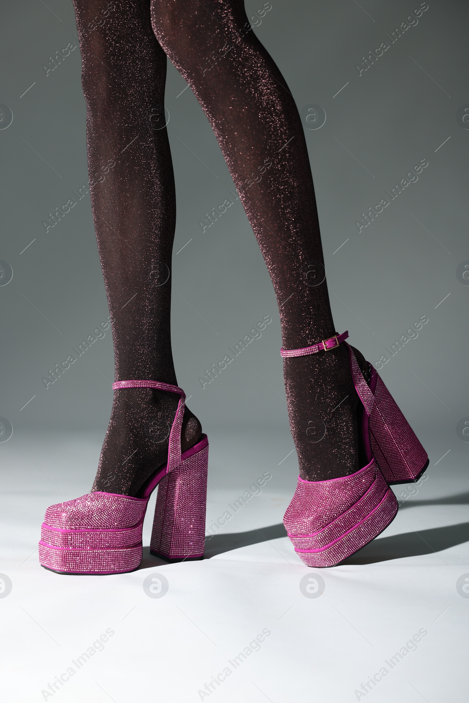 Photo of Woman wearing pink high heeled shoes with platform and square toes on light grey background, closeup