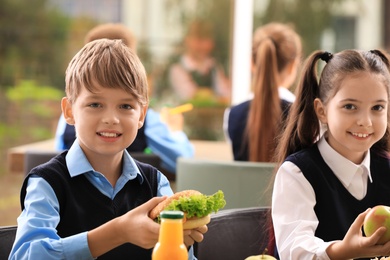 Happy children at table with healthy food in school canteen
