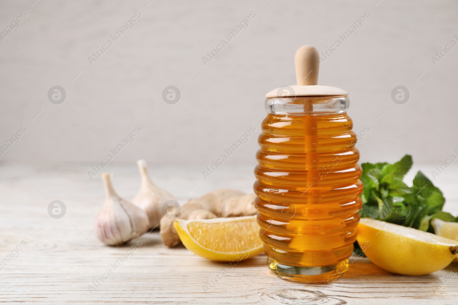 Photo of Jar of honey, ginger, garlic, mint and lemon on wooden table, space for text. Cough remedies